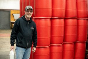 AFI Employee standing next to 200 pound barrels of fragrance oil