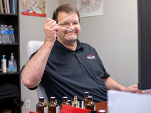An AFI perfumer evaluating a custom fragrance oil on a blotter strip