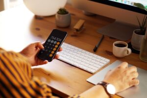 calculating prices at a computer with a phone calculator